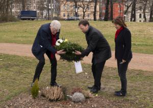 Drei Menschen legen einen Kranz nieder