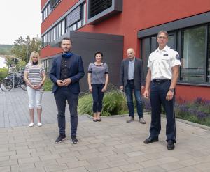 Fünf Menschen in einer Gruppe schauen in die Kamera