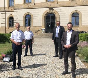 Vier Personen stehen vor einem Haus im Abstand von 1,5 m.