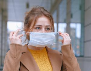 Eine Frau zieht eine Mund-Nase-Bedeckung auf. 