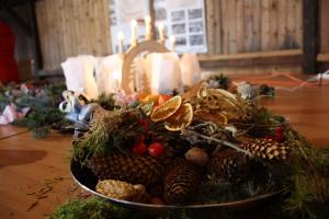 Ein weihnachtliches Gesteck, im Hintergrund brennen Kerzen