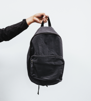 Eine Hand hält einen Rucksack in die Luft