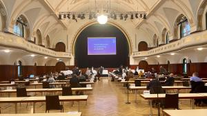 Ein großer Saal mit Tischen, an denen Menschen sitzen