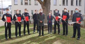 Acht Männer und eine Frau schauen in die Kamera, alle tragen Masken