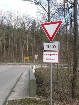 Eine Einmündung in eine Bundesstraße mit einem Schild mit dem Vermerk Geflügelpest, Sperrbezirk