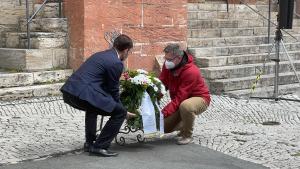 Zwei Männer legen einen Kranz nieder