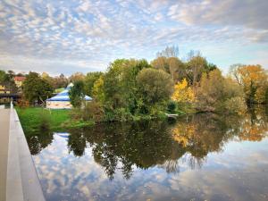 Im Vordergrund ein Fluss mit einer Brücker und im Hintergrund ein Zirkuszelt im Grünen