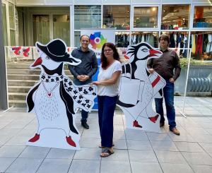 Drei Menschen schauen in die Kamera und haben Pappaufsteller dabei