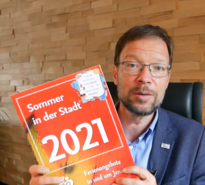 Ein Mann hält eine Broschüre in die Kamera