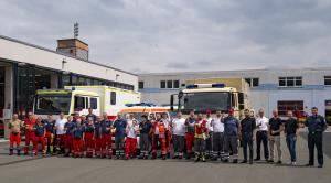 Viele Menschen vor Einsatzfahrzeugen des Katastrophenschutzes