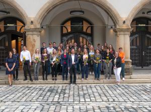 Eine große Anzahl an Personen steht im Außernbereich vor einem Gebäude