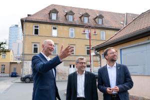 3 Männer im Außenbereich sehen sich etwas gemeinsam an.