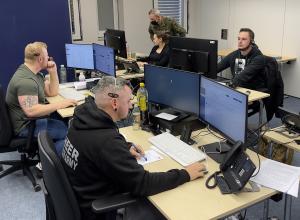 Vier Personen in einem Raum am Telefon