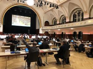 Viele Menschen in einem Saal bei einer Abstimmung