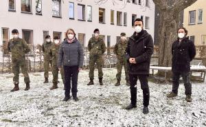 Menschen stehen in einer Schneelandschaft, darunter fünf Soldaten