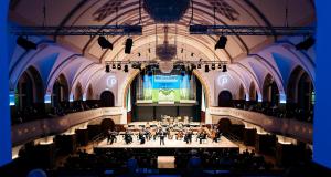 Blick in das Volksbad die Wände sind blau angeleuchtet in der Mitte die Bühne mit den Musiker:innen der Jenaer Philharmonie