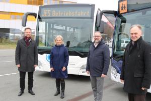 Vier Menschen vor zwei Bussen