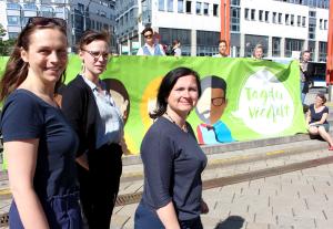 Drei Frauen stehen vor einem Plakat auf dem "Tag der Vielfalt" steht.