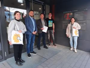 Mehrere Personen stehen vor  der Glastür eines Gebäudes