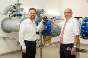 Zwei Männer vor großen Wasserrohren