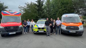 Rettungswagen mit Personen, die in die Kamera schauen