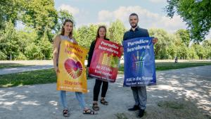 Drei Personen halten je ein Plakat in die Kamera