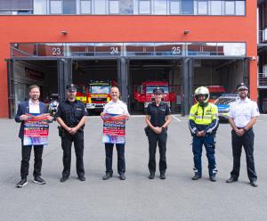 Feuerwehrleute und Polizisten vor einer Feuerwehr mit geöffneten Toren