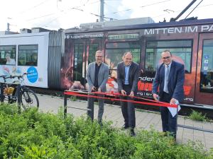 Drei Männer zerschneiden das symbolische rote Band.
