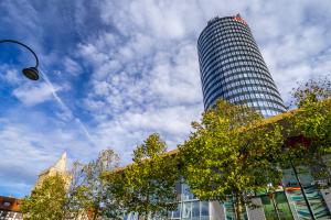 Ein großer Turm ragt zwischen viel Grün hervor.