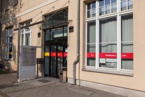 Blick auf ein Gebäude mit Hinweistafel und großer automatischer Tür