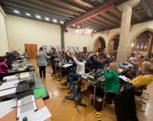 Ein großer Raum mit Menschen, welche abstimmen