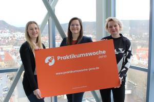 Drei Frauen halten ein Schild in die Kamera