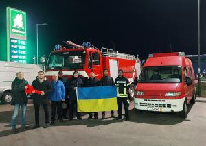 Menschen stehen vor mehreren Feuerwehrfahrzeuge