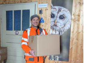 Ein Mitarbeiter des Wertstoffhofes hält eine Umzugskiste.