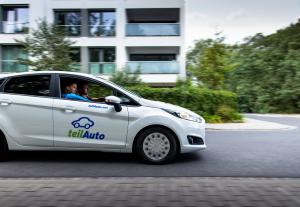 Ein Auto des Carsharing-Anbieters teilAuto fährt durch ein Wohngebiet