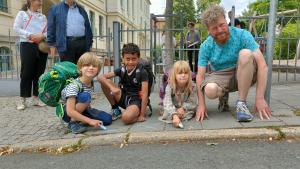 Die 7-jährigen Kinder Justus, Josef und Marla mit Erzieher Tino Buschbeck (v.l.) markieren ihren Schulweg mit Kreide. (Credit: Stadt Jena)