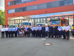 Gruppenbild der Fluthelfer*innen, Oberbürgermeister Thomas Nitzsche, Sicherheitsdezernent Benjamin Koppe und Oberbranddirektor Peter Schörnig vor Fahrzeugen des Katastrophenschutz