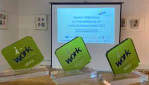 drei der i-work Unternehmenspreiss für interkulturelle Vielfalt stehen nebeneinander.