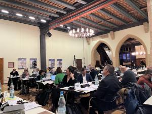 Im Rathaus-Plenarsaal sitzen Stadtratsmitglieder an Tischen