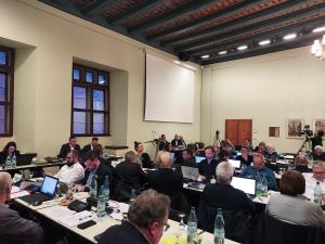 Mitglieder des Stadtrates sitzen an Tischen im historischen Rathaus