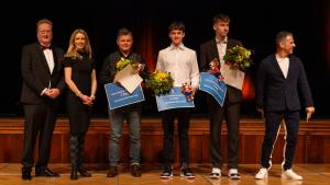 Auf der Bühne stehen 6 Personen. Die drei besten Nachwuchssportler nehmen ihre Auszeichnungen entgegen.