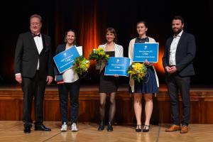 Auf der Bühne stehen 5 Personen. Die drei besten Trainer nehmen ihre Auszeichnungen entgegen.