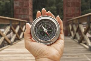 Hand hält Kompass auf einer Brücke