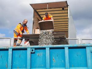 KSJ-Mitarbeiter schütten die abgeholten Kronkorken in einen Container.