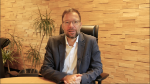 Oberbürgermeister Thomas Nitzsche sitzt am Tisch in seinem Büro und spricht seine Videobotschaft ein.