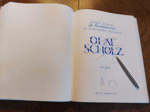 Das Goldene Buch der Stadt Jena liegt geöffnet auf dem Tisch. Man sieht den Eintrag des Bundeskanzlers Olaf Scholz