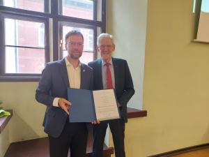 Oberbürgermeister DR. Thomas Nitzsche und Stadtrat Volker Blumentritt stehen nebeneinander, eine Urkunde in der Hand haltend