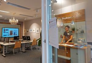 Blick in den Laden mit Stühlen, Tischen und Mann am Tresen.