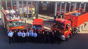 Gruppe von Feuerwehrmännern steht vor drei Feuerwehren.