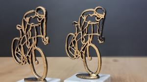 Zwei Pokale in Form eines stilisierten Fahrradfahrers mit Helm.